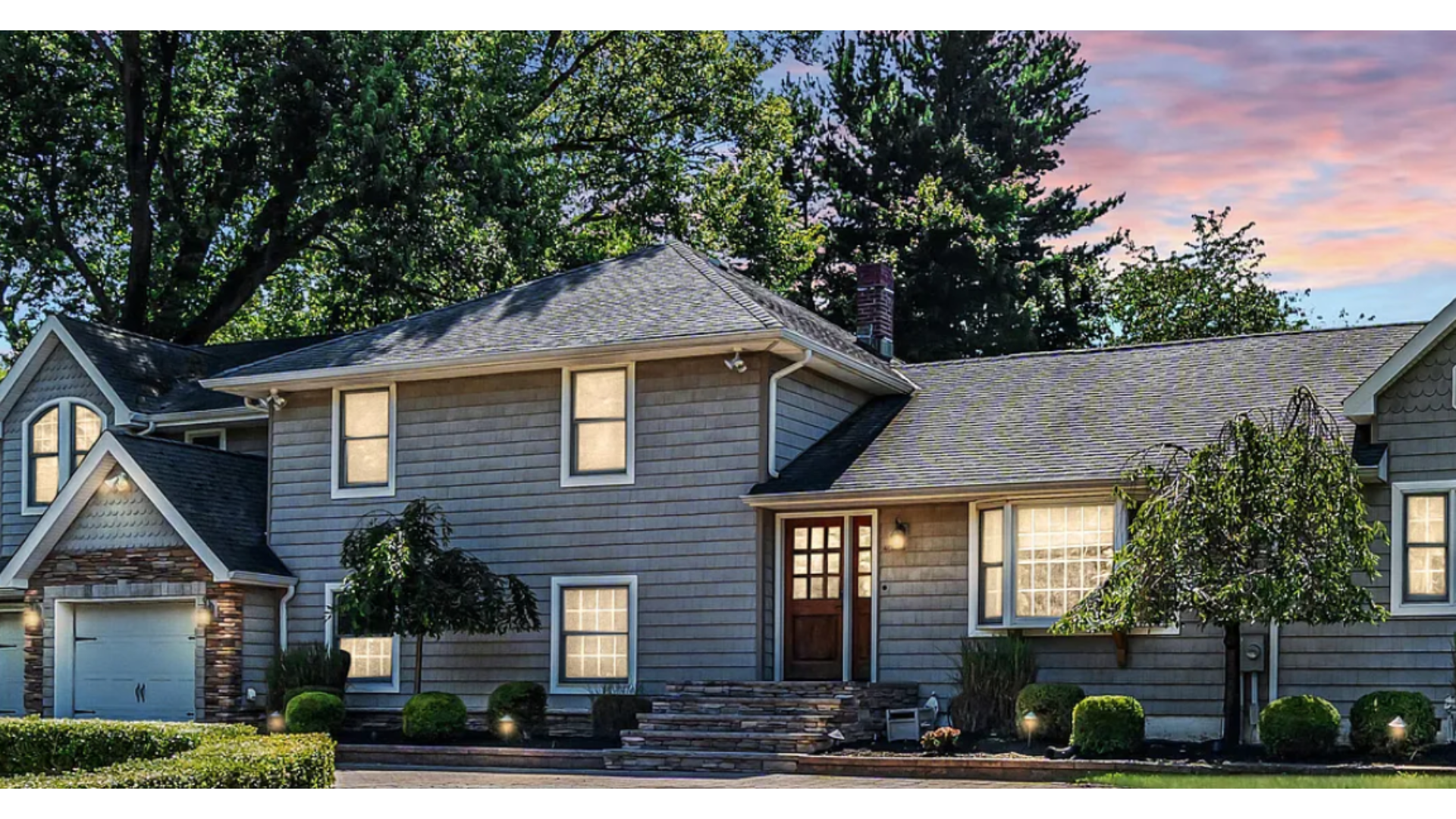 Modern split-level home in Holmdel, NJ with gray siding, stone accents, and a well-maintained roof. J.A.Y. Construction is a leading contractor for roofing and siding in Monmouth County.