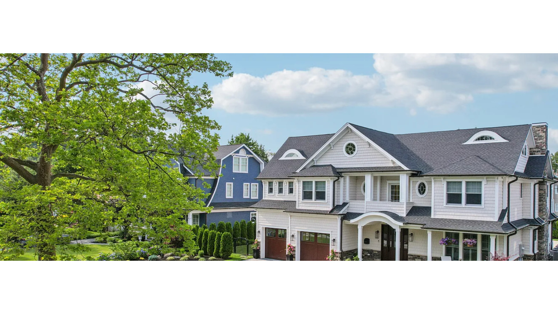 Coastal-style home in Sea Girt, NJ with gray shingles, white trim, and elegant rooflines surrounded by greenery. J.A.Y. Construction is a trusted roofing and siding expert along the Jersey Shore.