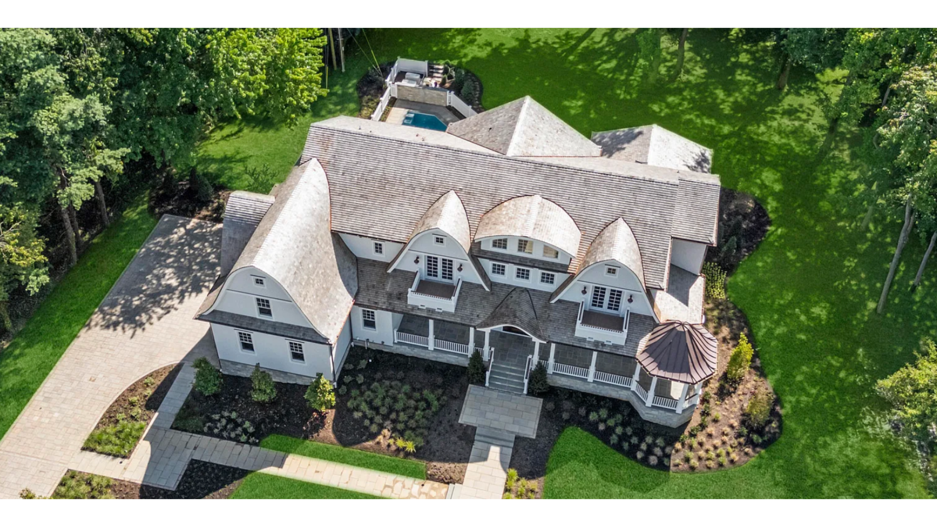 Aerial view of a luxury estate in Rumson, NJ with a cedar shake roof, manicured lawn, and pool. J.A.Y. Construction is a premier contractor for custom roofing and siding in Monmouth County.
