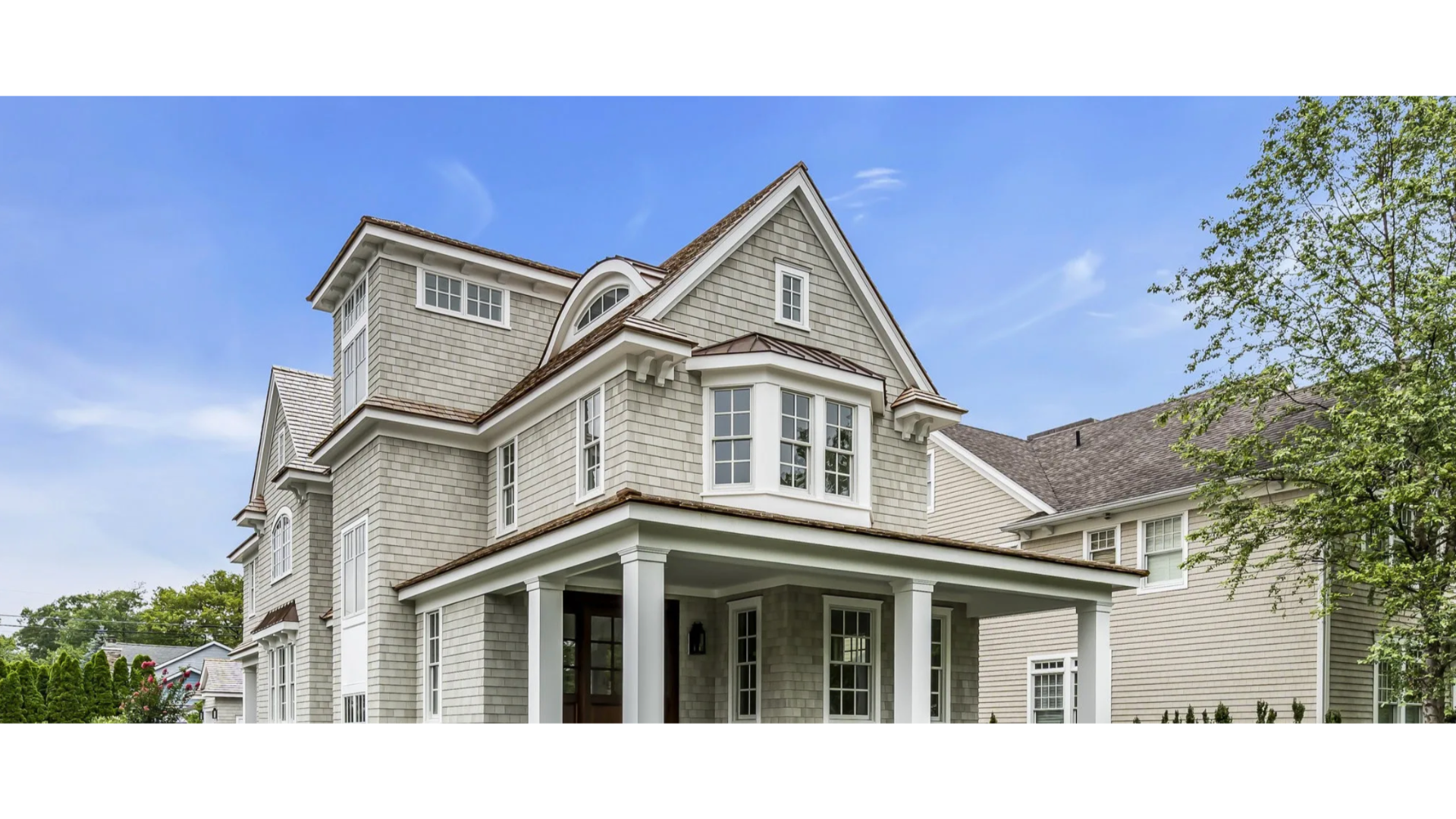 Elegant coastal-style home in Spring Lake, NJ with cedar shake siding, pitched roof, and covered porch. J.A.Y. Construction is a premier local expert in roofing and siding craftsmanship.