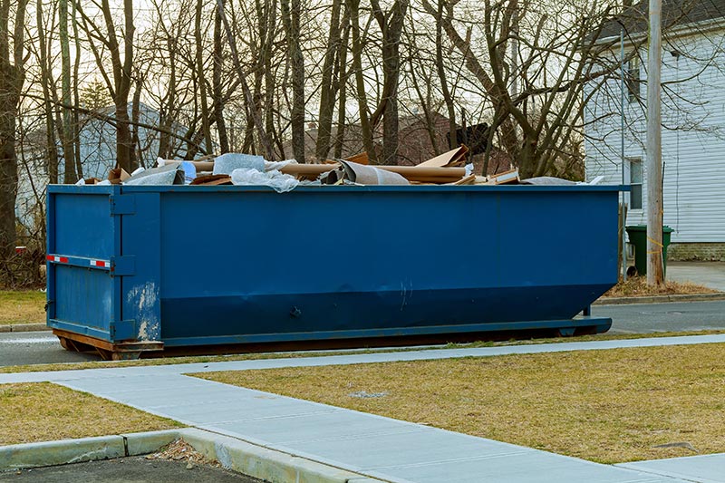 blue metal dumpster in the street during a home renovation 