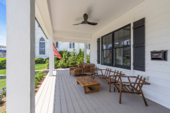 Covered porch of Manasquan NJ home with outdoor seating, black-framed windows, and ceiling fan by J.A.Y. Construction 