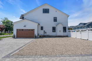 Rear driveway and garage of custom Manasquan NJ home with paver stone design and white fencing by J.A.Y. Construction 