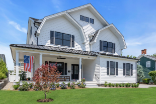 Angled view of Manasquan NJ custom home with American flag, covered porch, and black-framed windows by J.A.Y. Construction 