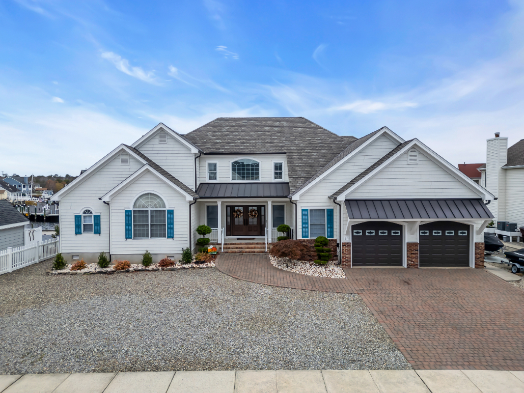 Custom double entry doors, standing seam metal roof, and carriage garage doors on waterfront home renovation in NJ