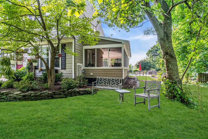 Side yard view of screened-in porch addition built by J.A.Y. Construction in Freehold NJ surrounded by mature landscaping