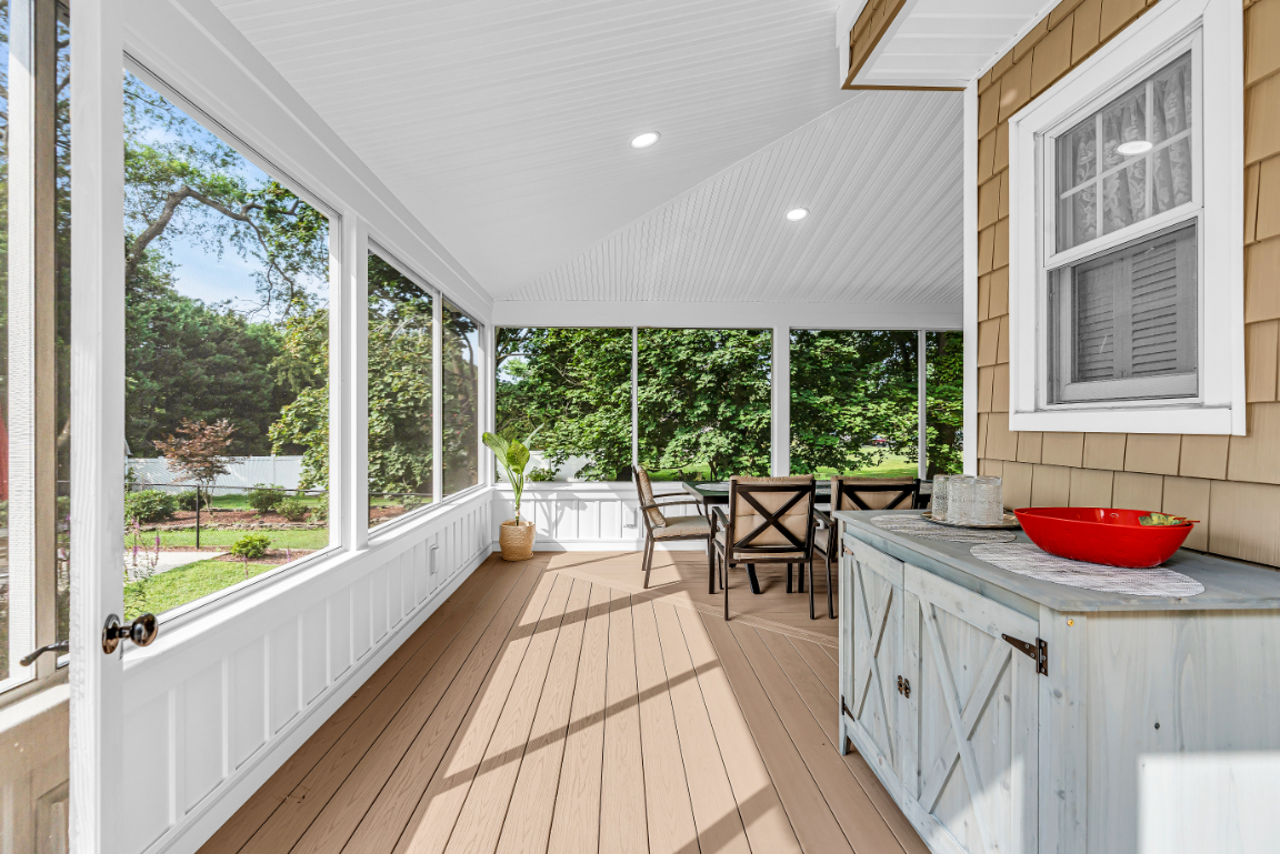 Interior view of screened porch with composite flooring, white trim, recessed lighting, and large screened openings