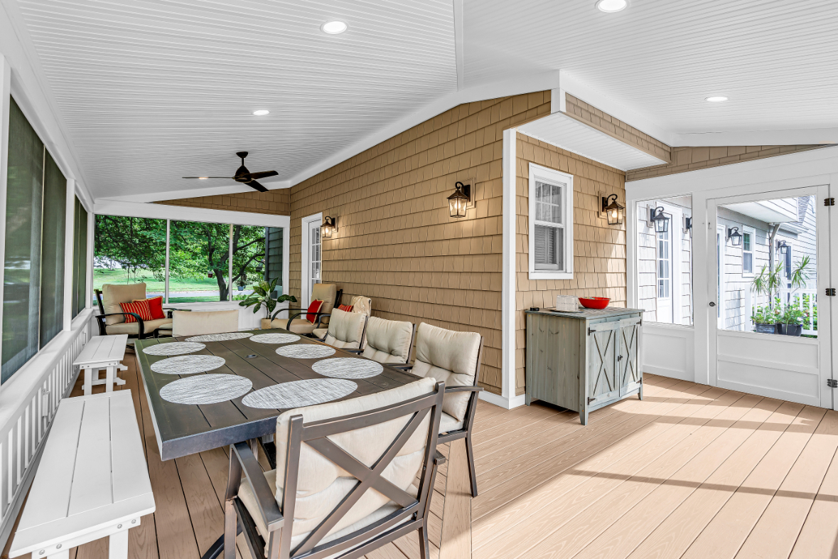 Wide interior angle of screened-in porch featuring dining area, ceiling fan, beadboard ceiling, and natural light