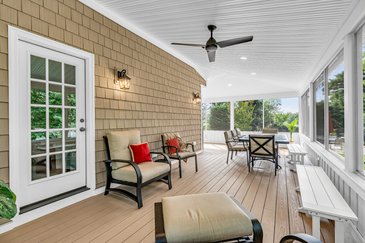 Interior of screened porch addition with composite deck flooring and open view to garden and trees