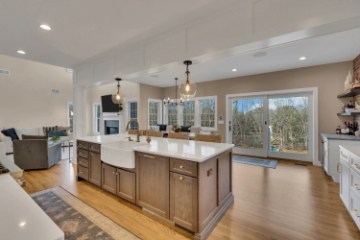 Open-concept kitchen and living room renovation by J.A.Y. Construction with large island, farmhouse sink, pendant lighting, and hardwood floors.