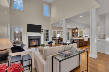 Open living room flowing into kitchen after full interior renovation by J.A.Y. Construction, featuring hardwood floors, white columns, and modern layout.