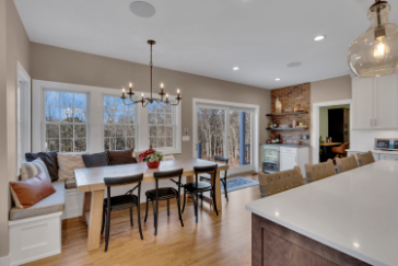 Modern kitchen and dining room renovation by J.A.Y. Construction featuring white cabinetry, large island with seating, hardwood floors, and open layout.