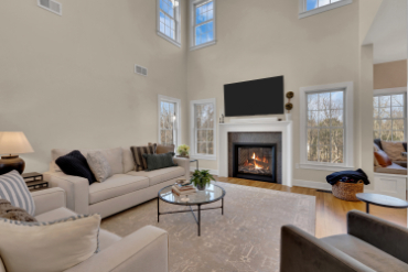 Open-concept living room renovated by J.A.Y. Construction featuring a gas fireplace, mounted TV, large windows, vaulted ceilings, and hardwood flooring.
