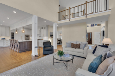 Open-concept interior renovation by J.A.Y. Construction showcasing living room seating, hardwood floors, kitchen island, and second-floor overlook.