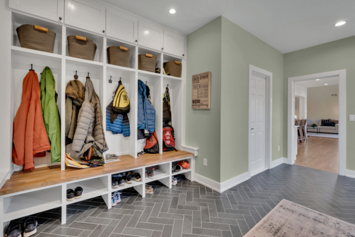 Custom mudroom renovation by J.A.Y. Construction with built-in cubbies, bench seating, coat storage, and gray herringbone tile flooring in a modern family home.