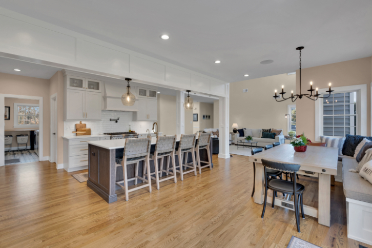 Dining area renovation by J.A.Y. Construction with built-in bench seating, hardwood floors, modern chandelier, and large windows overlooking backyard.