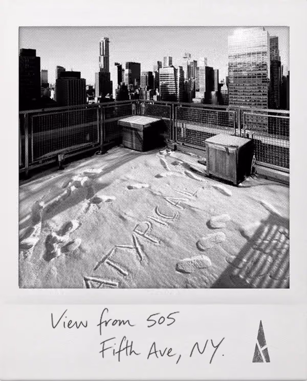 Polaroid picture of a rooftop scene with ATYPICAL written in the snow and city skyline in background