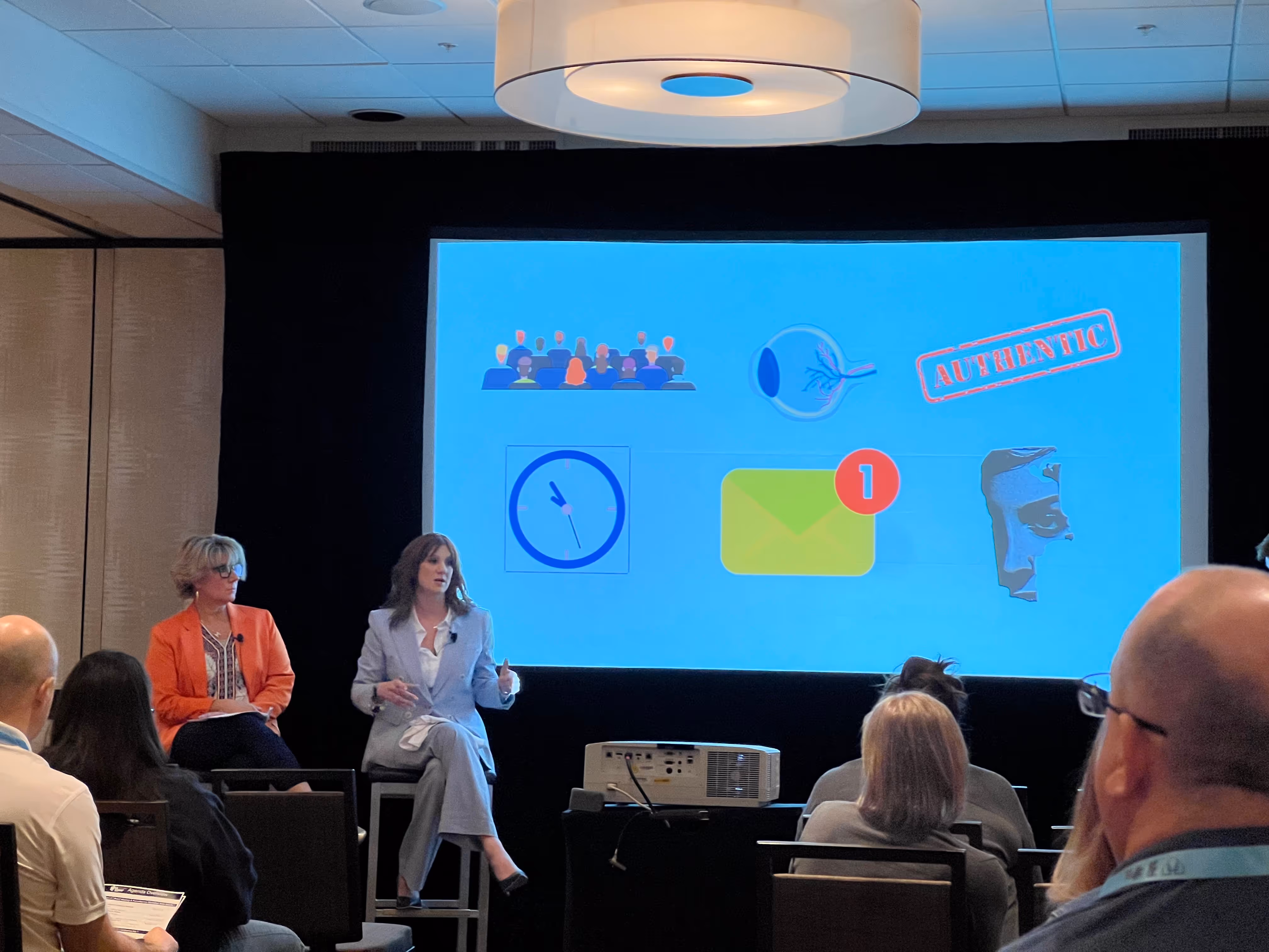 Panelists speaking on stage with presentation