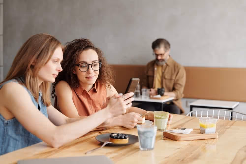 Two women using phone.