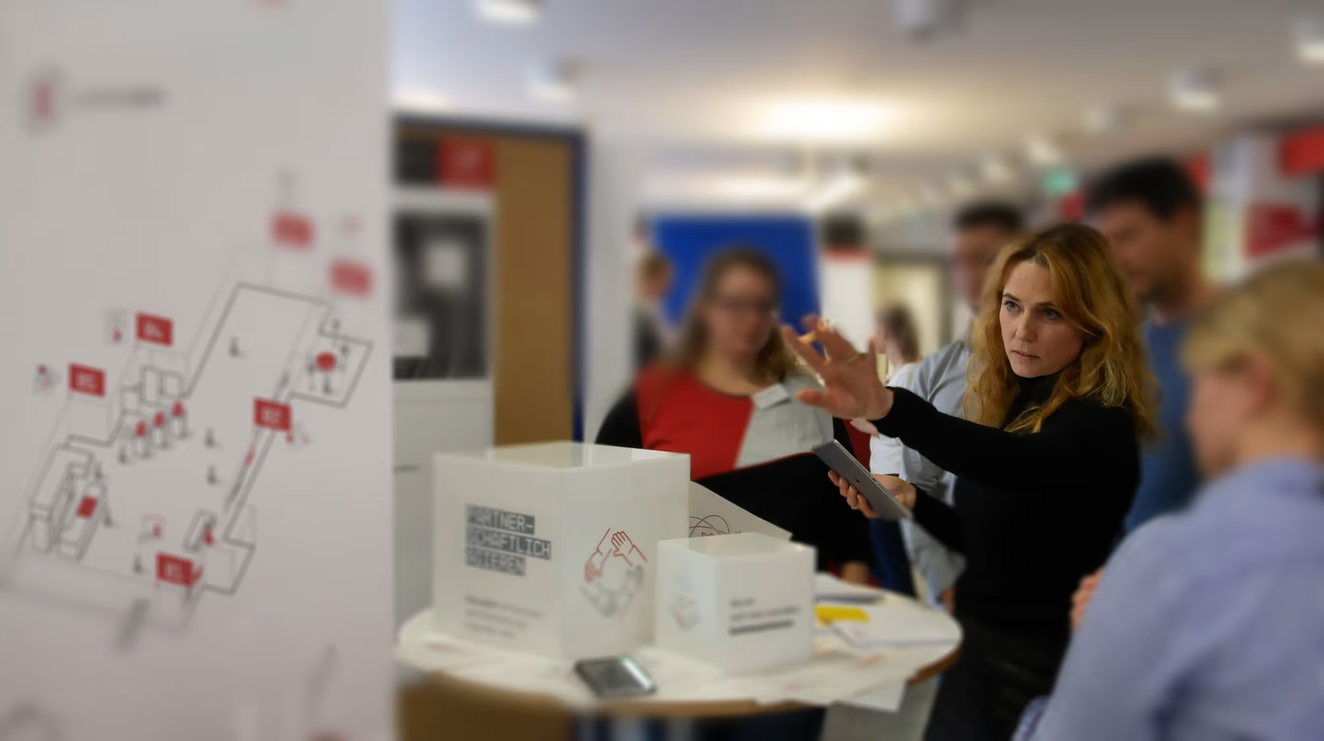 Astrid Paul erklärt Messebesuchern Ausstellungskonzept.