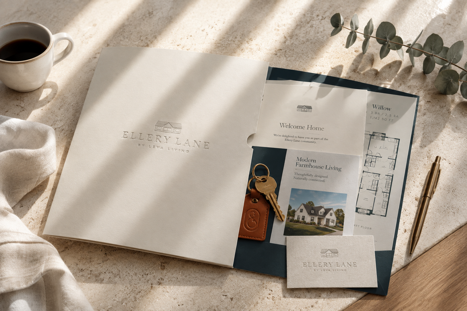 Ellery Lane welcome packet with branded folder, floor plan, welcome card, business card, and leather key tag arranged on a light stone surface with soft natural light.