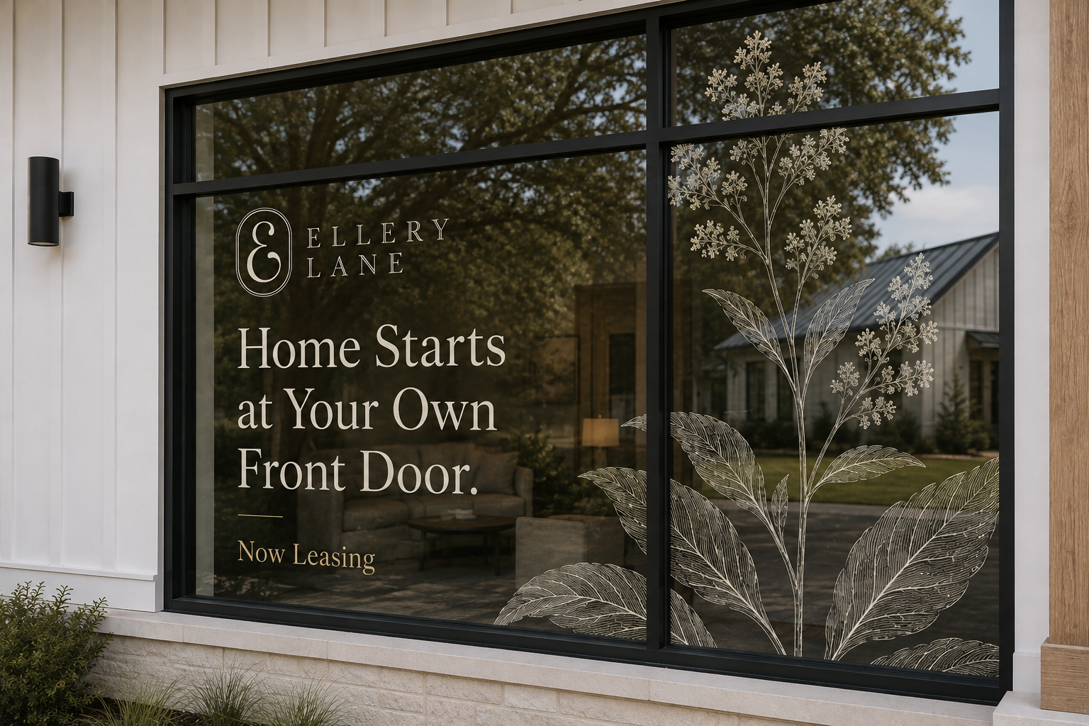 Ellery Lane leasing window display featuring the logo, “Home Starts at Your Own Front Door.” messaging, and oversized botanical line art applied to black-framed glass overlooking the cottage community.
