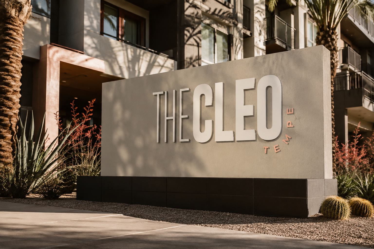 The Cleo Tempe monument sign featuring dimensional cream and blush lettering, surrounded by desert landscaping and modern apartment architecture.