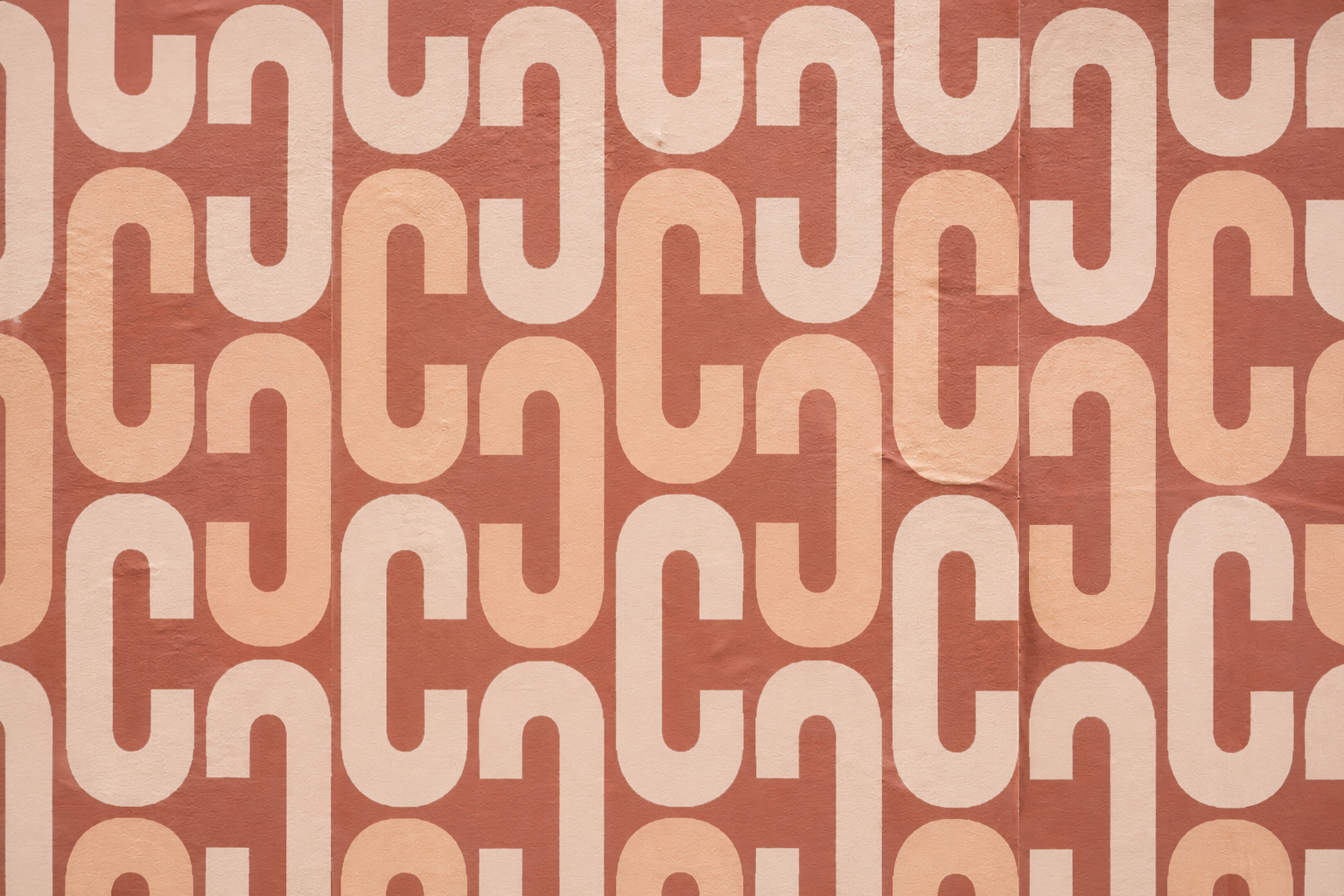 The Cleo’s repeating geometric pattern in warm cream and blush tones applied across a textured wall.