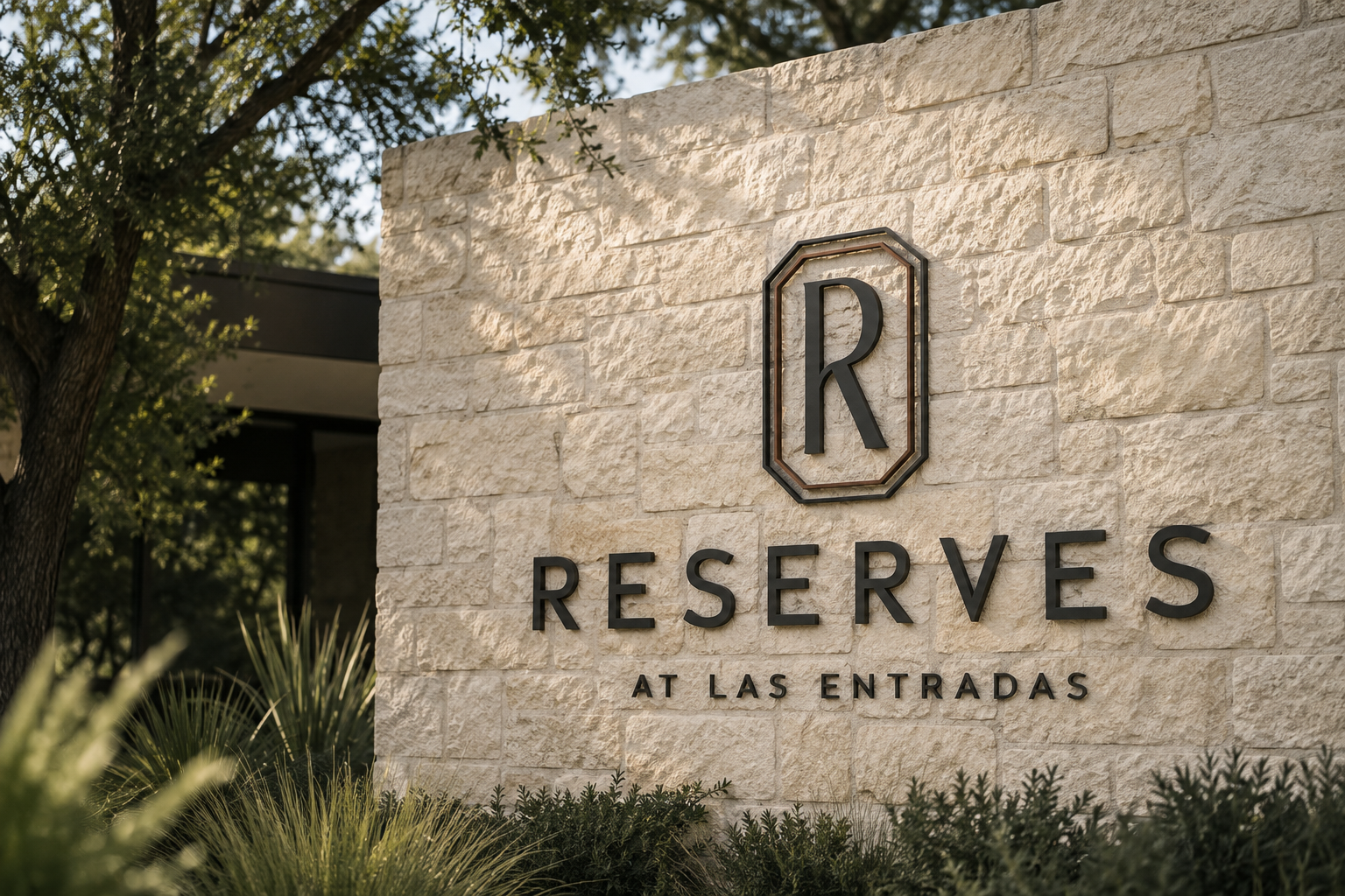Reserves at Las Entradas monument sign featuring the property’s dimensional logo and monogram on a limestone wall surrounded by native Texas landscaping.
