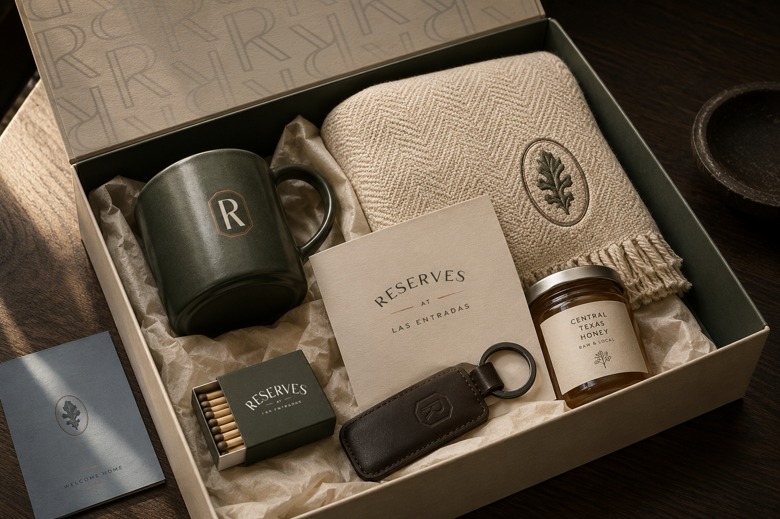 Reserves at Las Entradas welcome box featuring branded home essentials, including a ceramic mug, woven throw, keychain, matchbox, local Texas honey, and welcome materials.