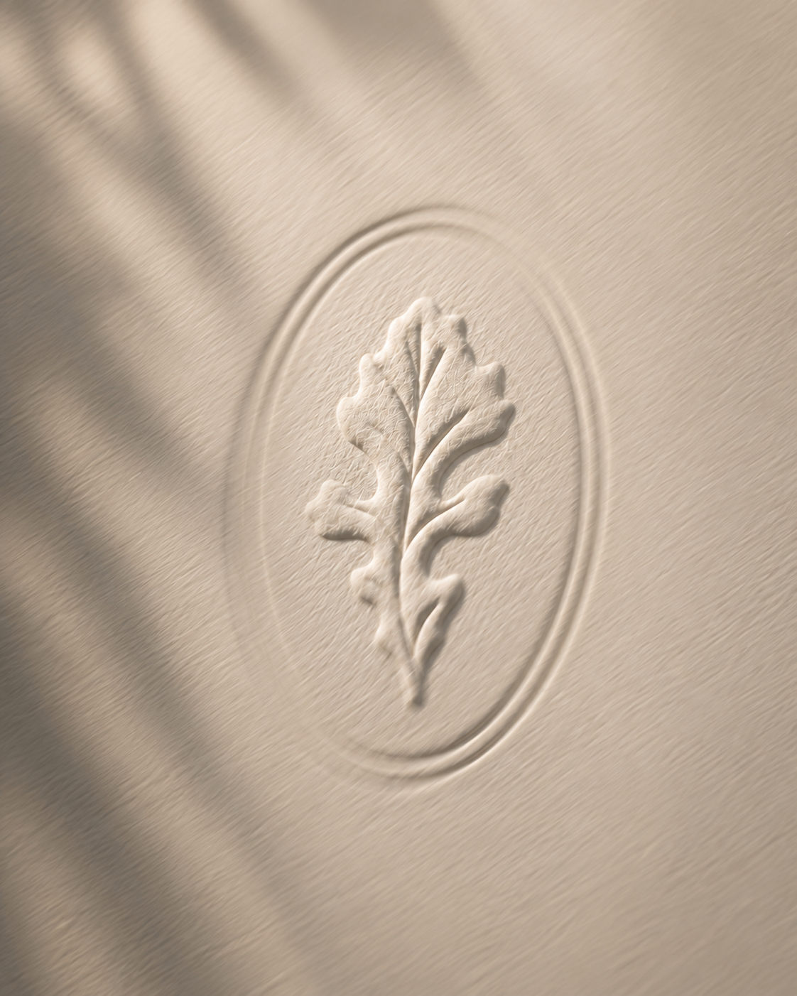 Close-up of the Reserves at Las Entradas oak leaf mark embossed into textured cream paper, illuminated by soft natural light and subtle shadows.