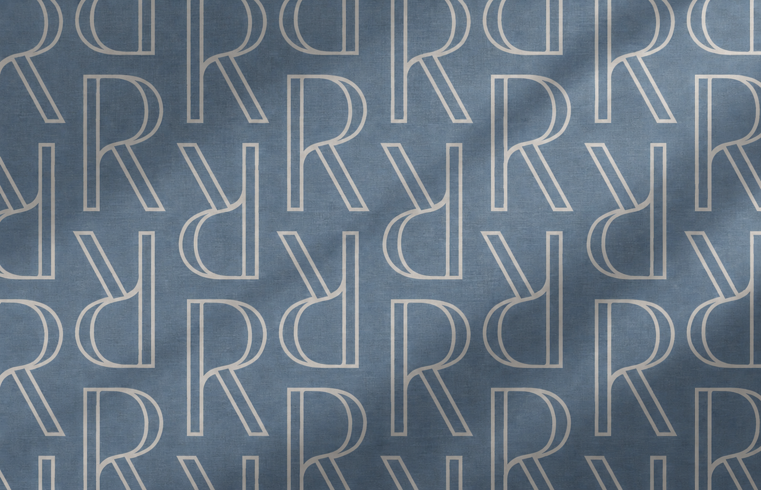 Repeating Reserves “R” monogram pattern in warm cream on a textured slate blue background.