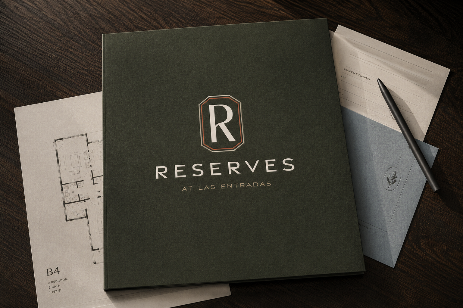 Reserves at Las Entradas branded leasing folder arranged with floor plans, residence materials, and a pen on a dark wood table.