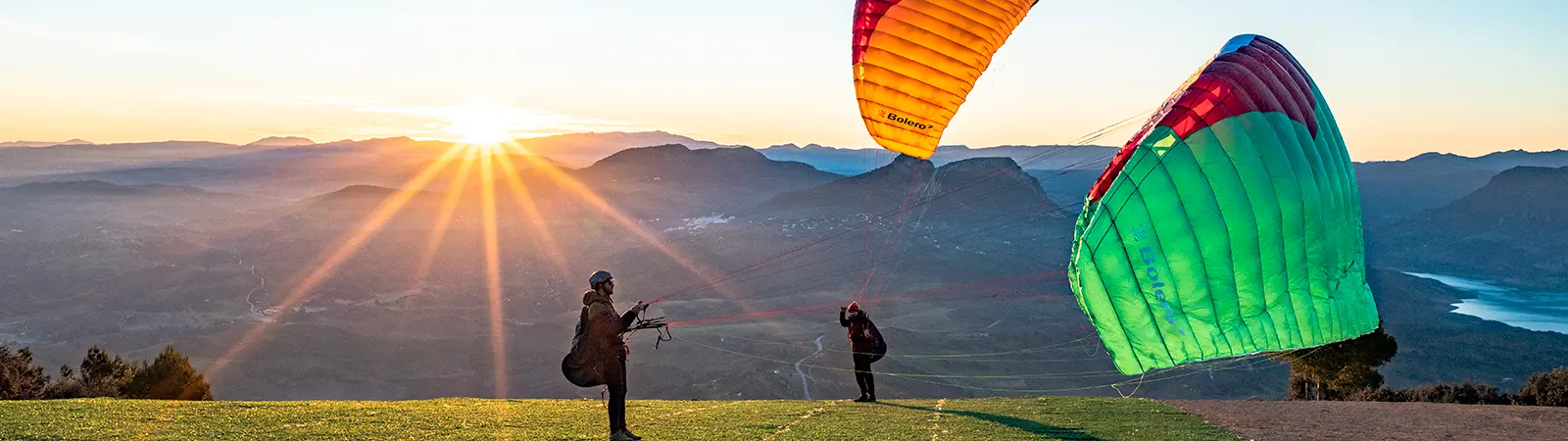 Image de parapentistes faisant du gonflage au lever du soleil