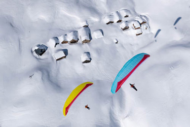 Image de deux parapentistes en vol au-dessus de la neige