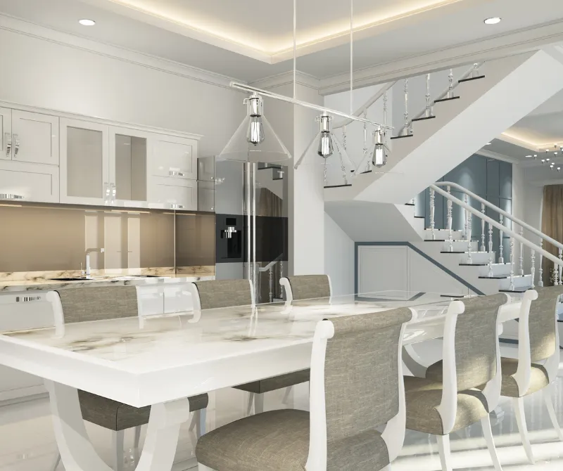 Modern kitchen with white and gray decor featuring a marble dining table, upholstered chairs, stainless steel refrigerator, and a staircase in the background.