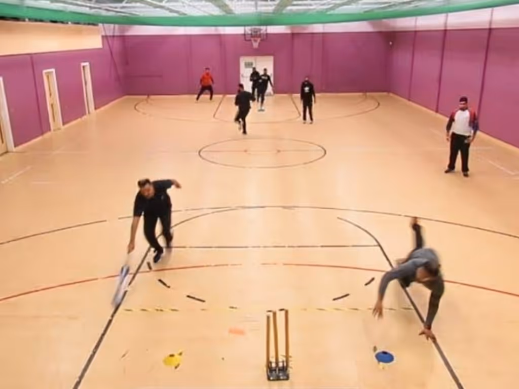 action shot of a fielder diving to run out a batter during an indoor cricket match at YMA