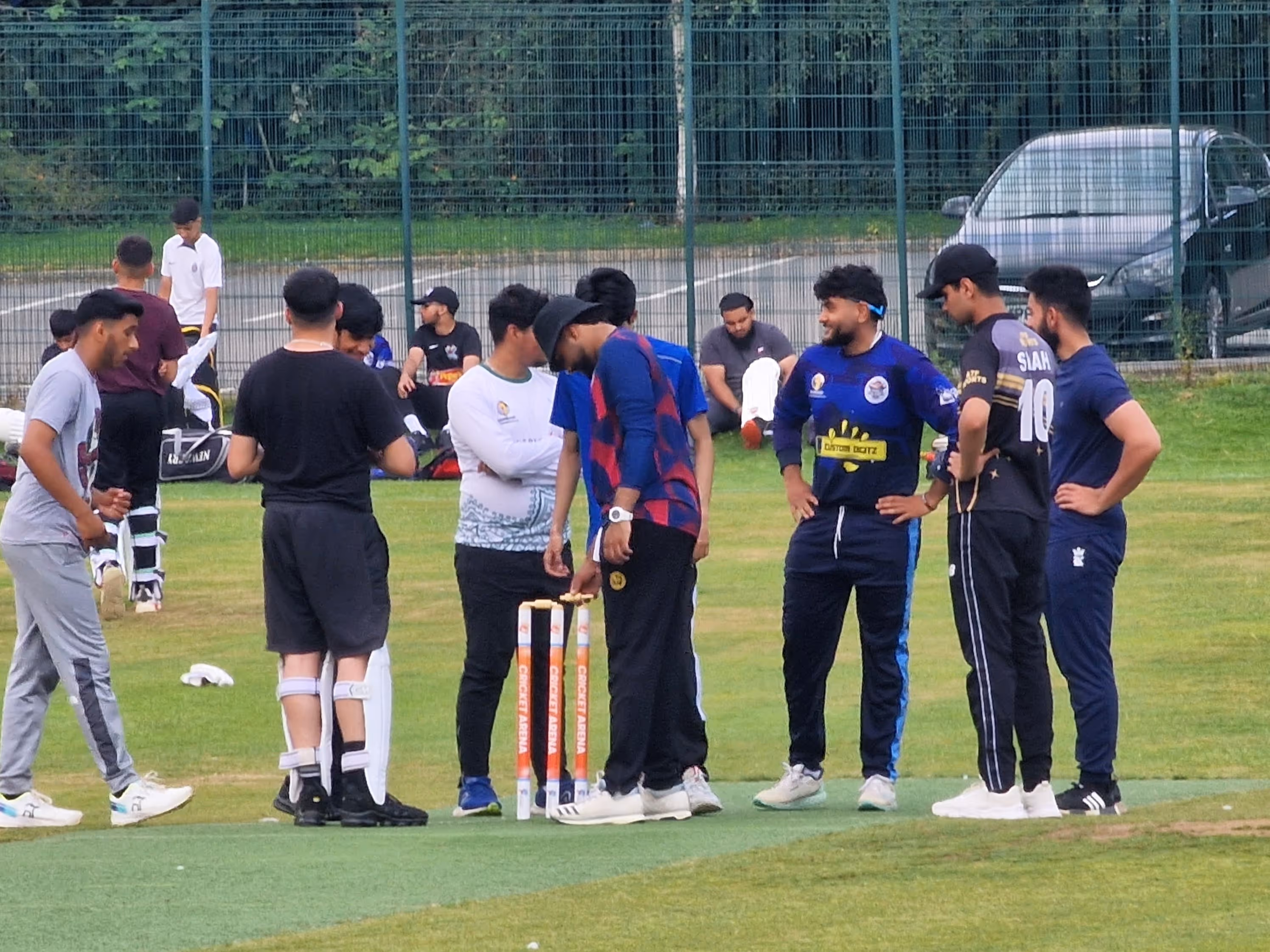 Players from the Cricket Arena Youth Hundred team gather to discuss tactics after a wicket falls, while watching the next batter prepare to enter