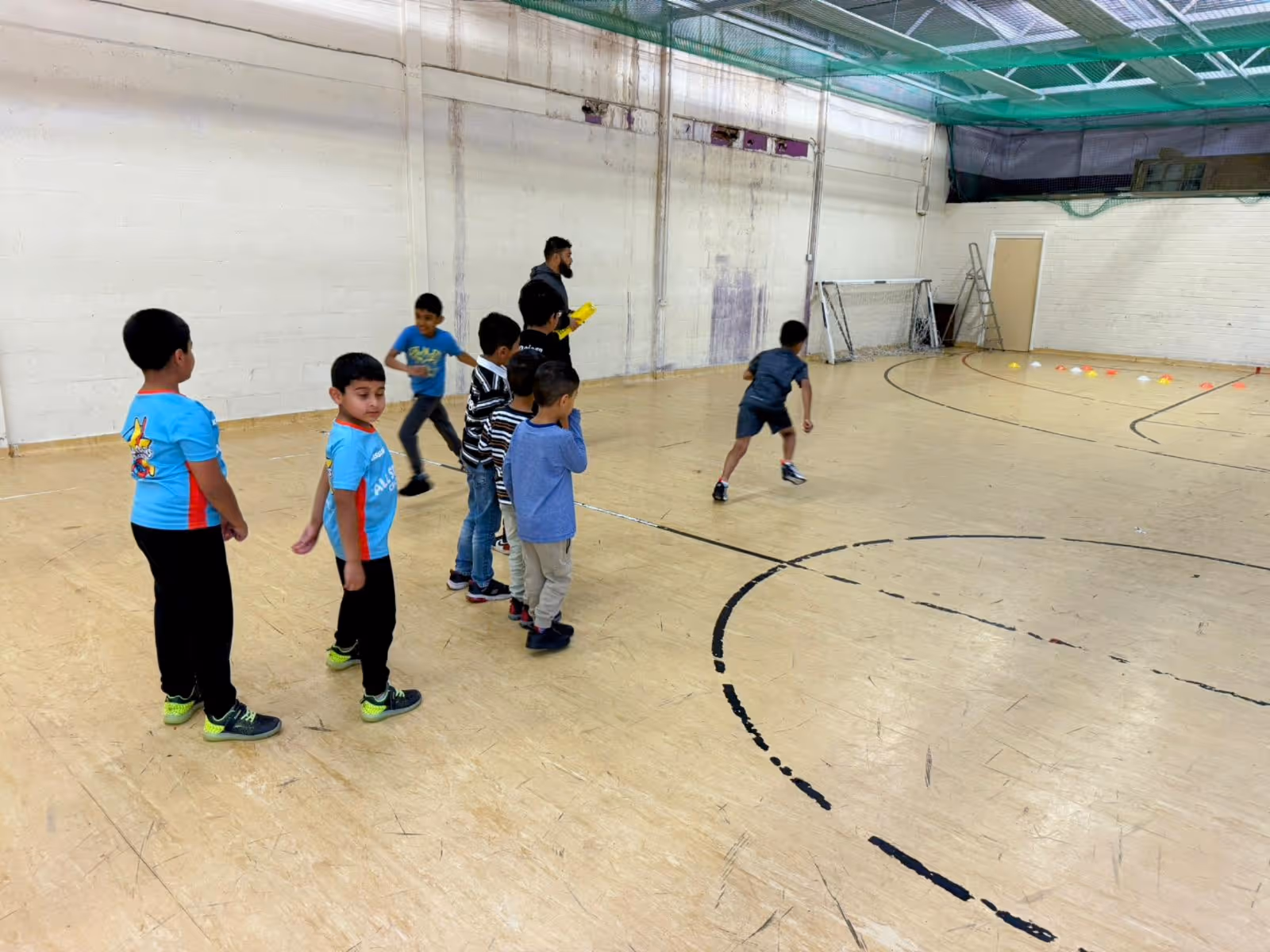 ECB-qualified head coach leading a running and cone-grab exercise during a Cricket Arena All Stars Cricket session at Yorkshire Muslim Academy in Sheffield.
