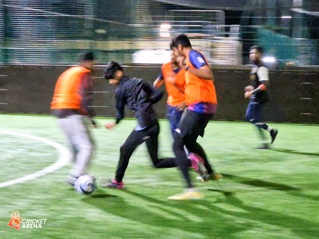 Youth players competing during a Cricket Arena Youth Sports Club football session under lights at the Soccer Centre in Sheffield, showing energy and teamwork.