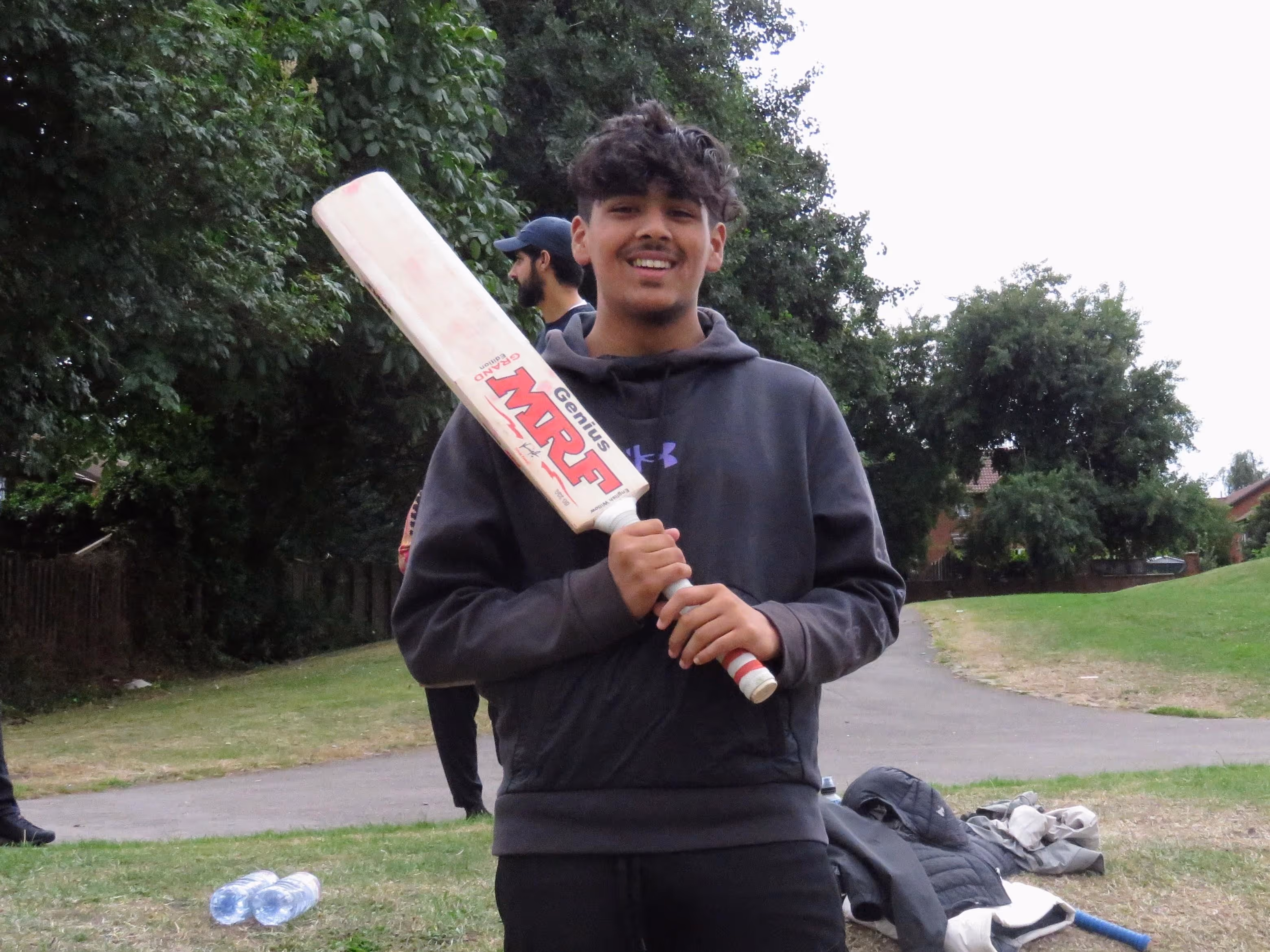 Hasan Ali, captain and best batter of the Junior Hundred 2022, smiling proudly while holding his MRF cricket bat after leading his team to victory.