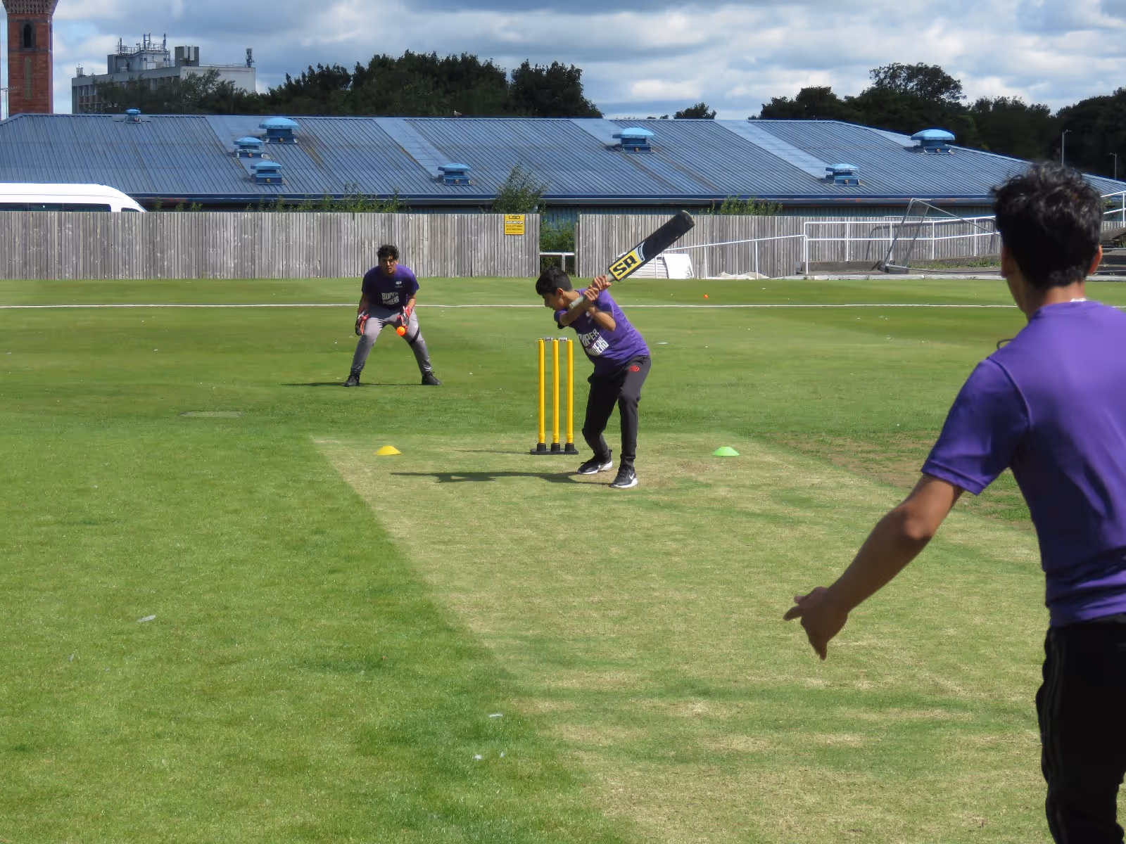 Action shot from the Junior Hundred 2022 at Park Avenue showing bowler, batter and keeper in one frame on the grass wicket as Sheffield bowl to Leeds.