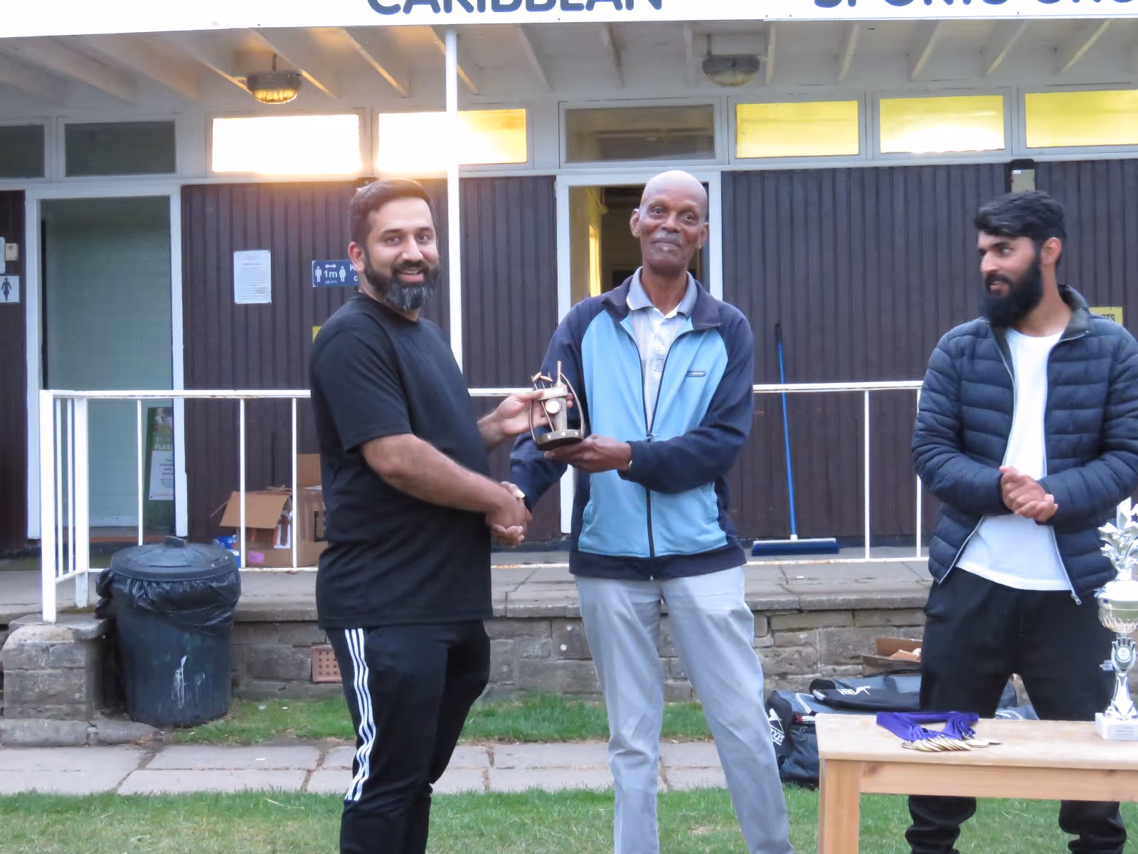 Adeel Malik receives the Man of the Final award from club legend and umpire Sam Gittens during the post-match ceremony at Caribbean Sports Club.