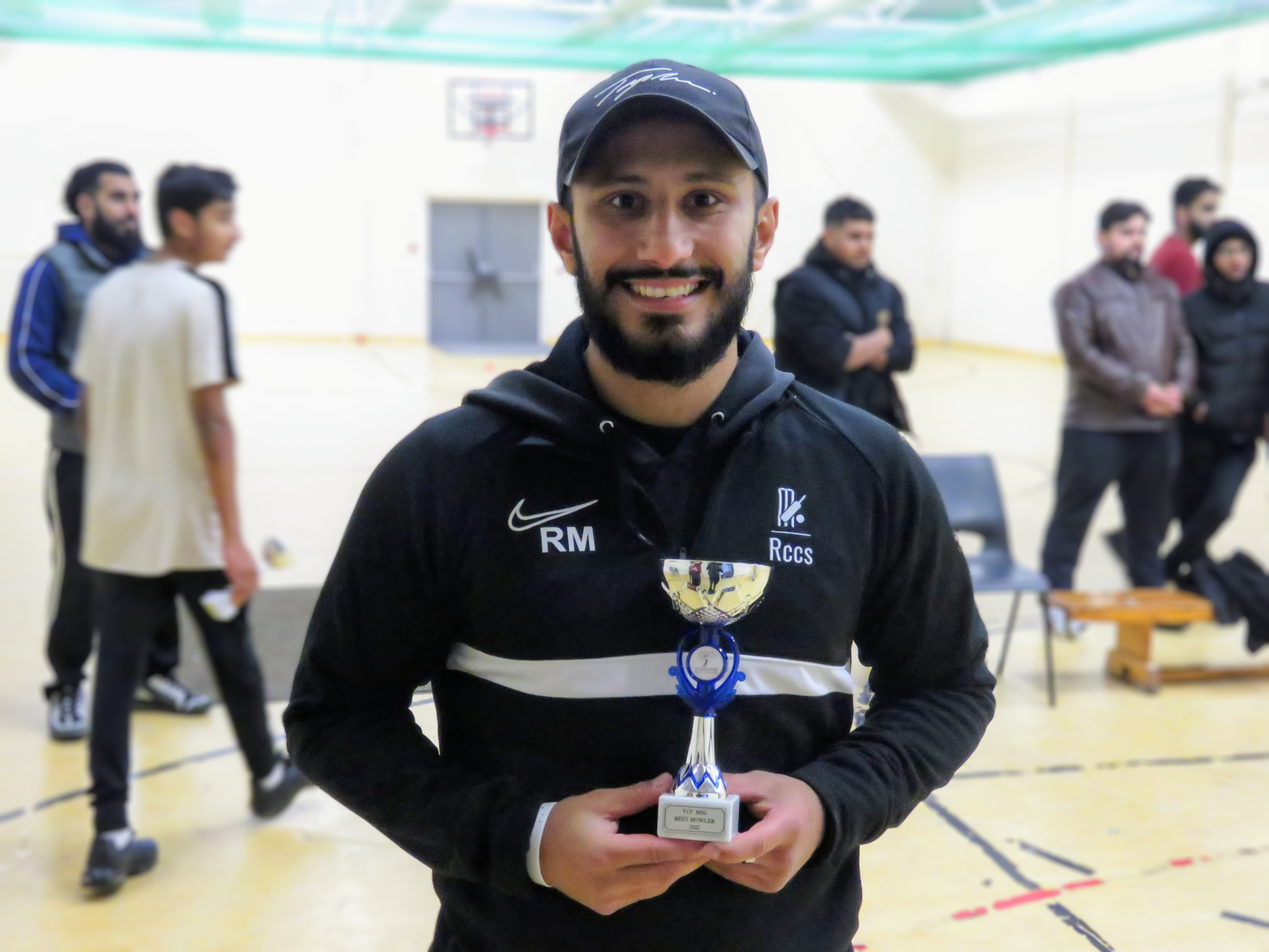 Rehan Mir smiles holding his MVP trophy in RCCS kit after winning player of the tournament at YMA Sheffield