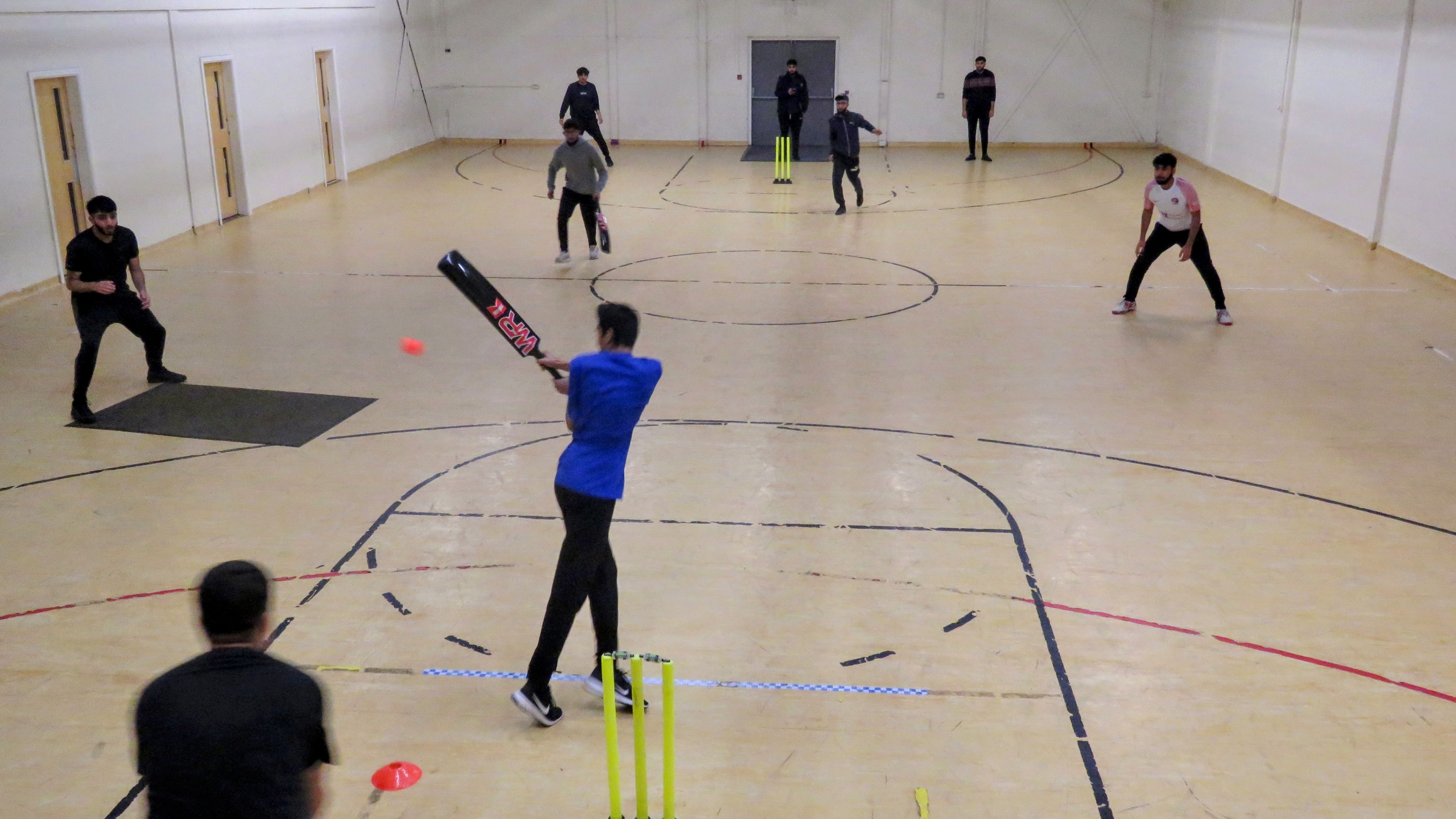 Indoor cricket match in MBL 2022 as batter plays a shot, showing youth action and community sport in Sheffield