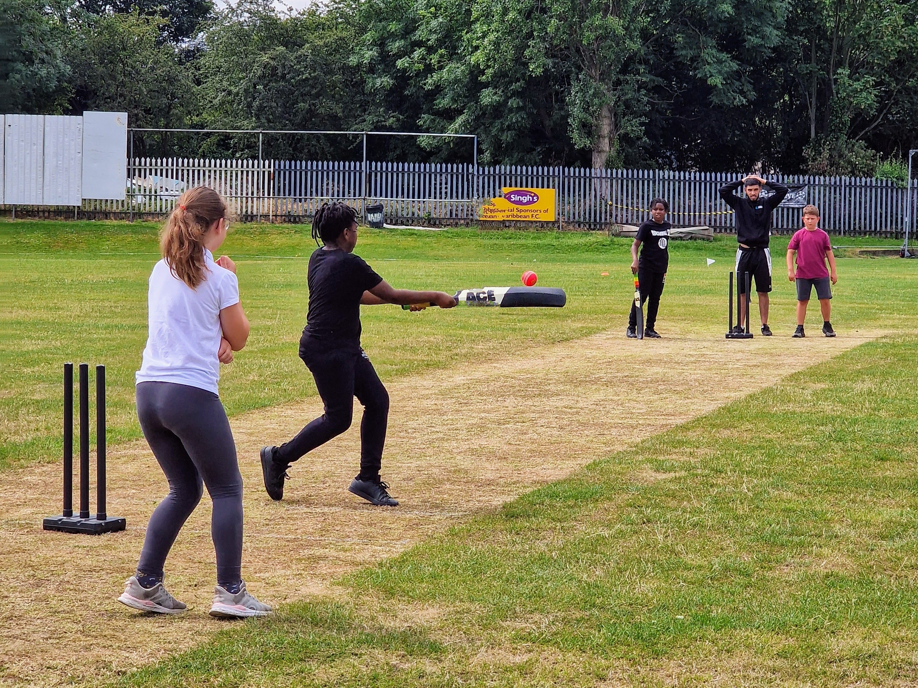 Youngsters playing windball cricket on grass at Sheffield Caribbean Sports Club, led by Cricket Arena volunteers during Windrush 75.