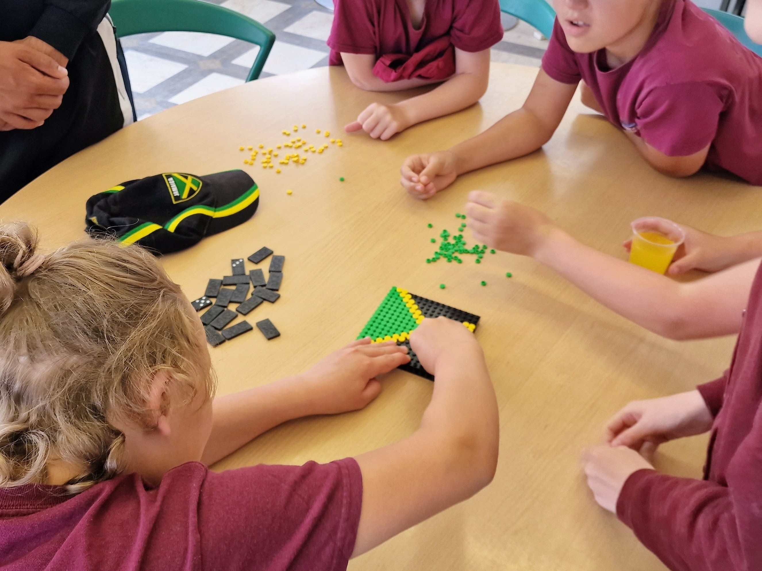 School children creating Jamaican flags with Lego and playing dominoes during Windrush 75 celebration activities.