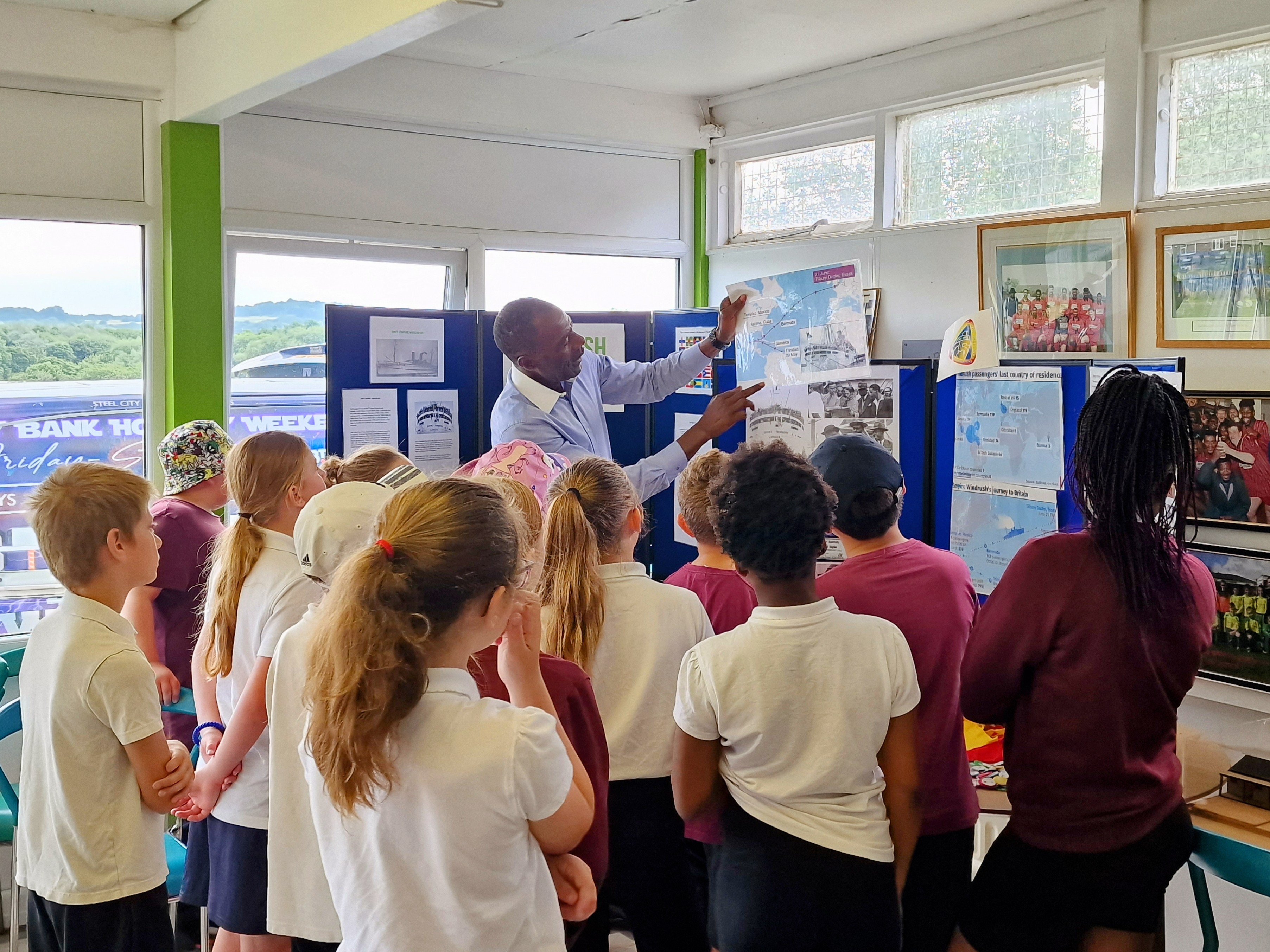 Des Smith teaching school children about Windrush history using educational display boards at Sheffield Caribbean Sports Club.