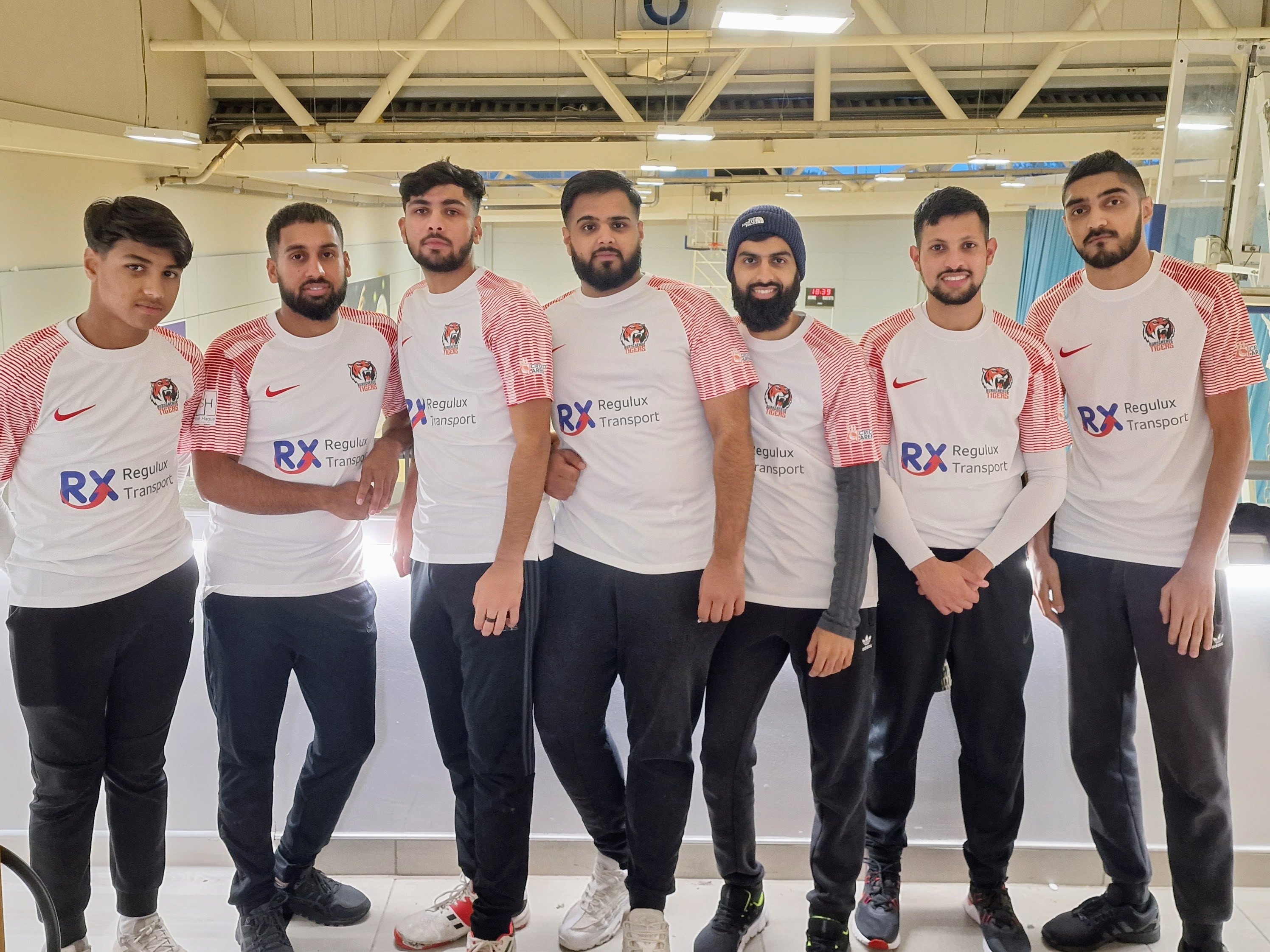 Burngreave Tigers team stand together on the EIS balcony in their white and red Nike kits, proudly displaying main sponsor Regulux Transport — showcasing team spirit and professional presentation.