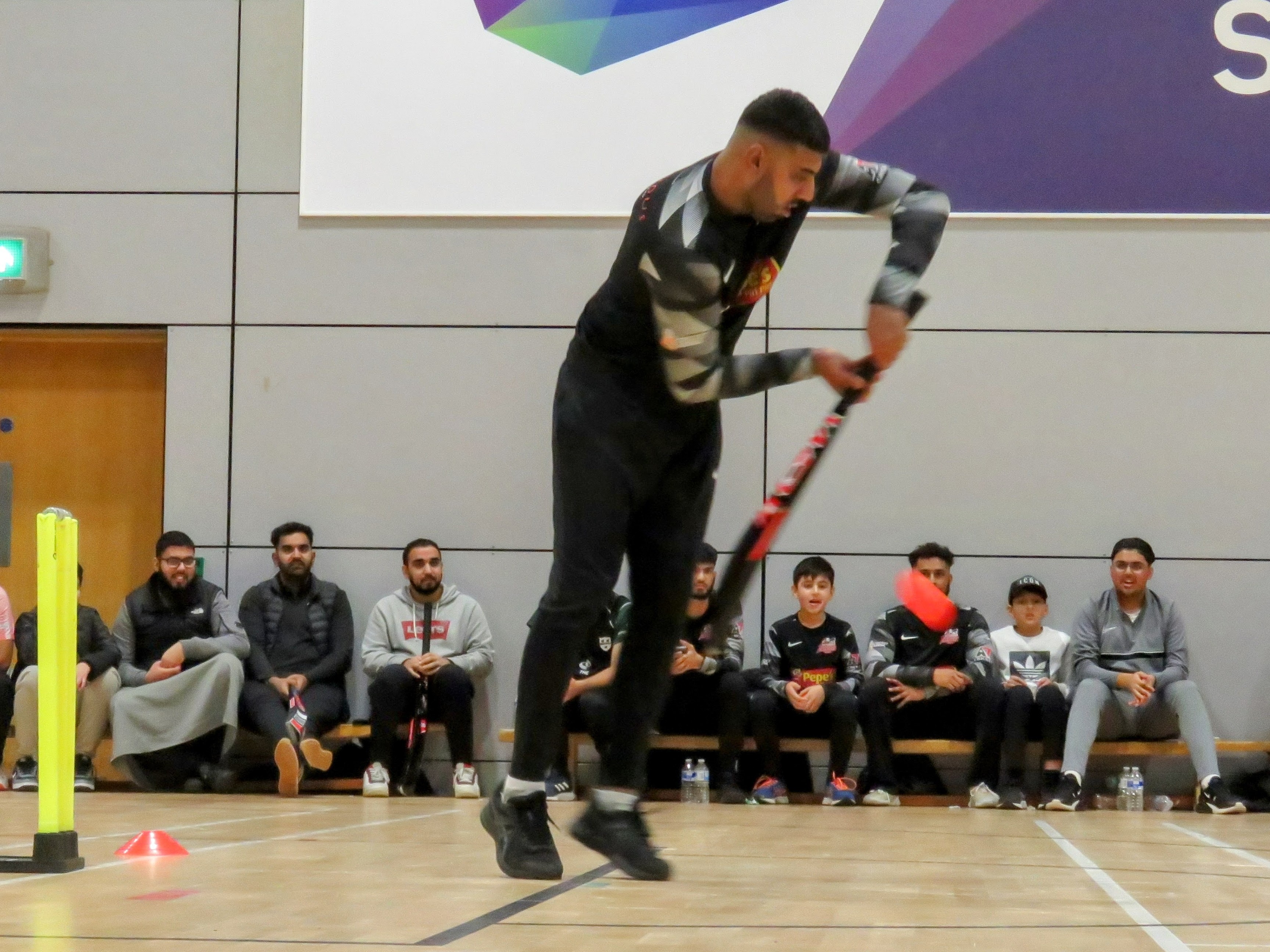From the leg umpire’s view, Saqib Hussain defends a delivery during the BBICL final at the English Institute of Sport. Behind him, teammates and supporters watch attentively from the benches — a moment reflecting community spirit and youth inspiration